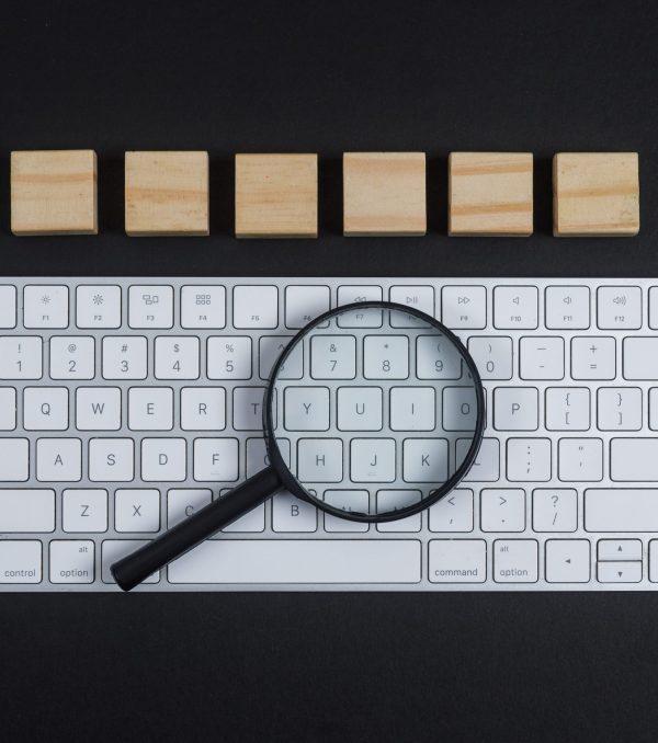 Conceptual of research with keyboard, magnifier, wooden cubes on black desk background flat lay. horizontal image
